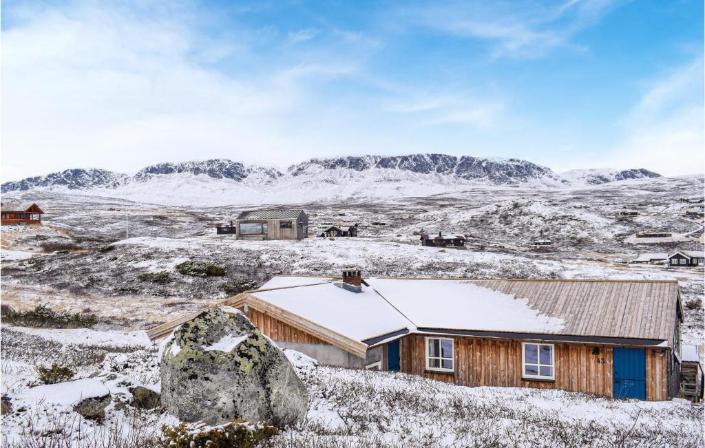 een houten hut in een besneeuwd veld met bergen op de achtergrond bij Beautiful Home In Ustaoset With House A Mountain View in Ustaoset