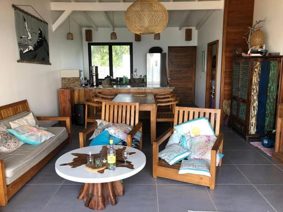 ein Wohnzimmer mit Sofa, Tisch und Stühlen in der Unterkunft Beach House à Terre de Haut in Terre-de-Haut