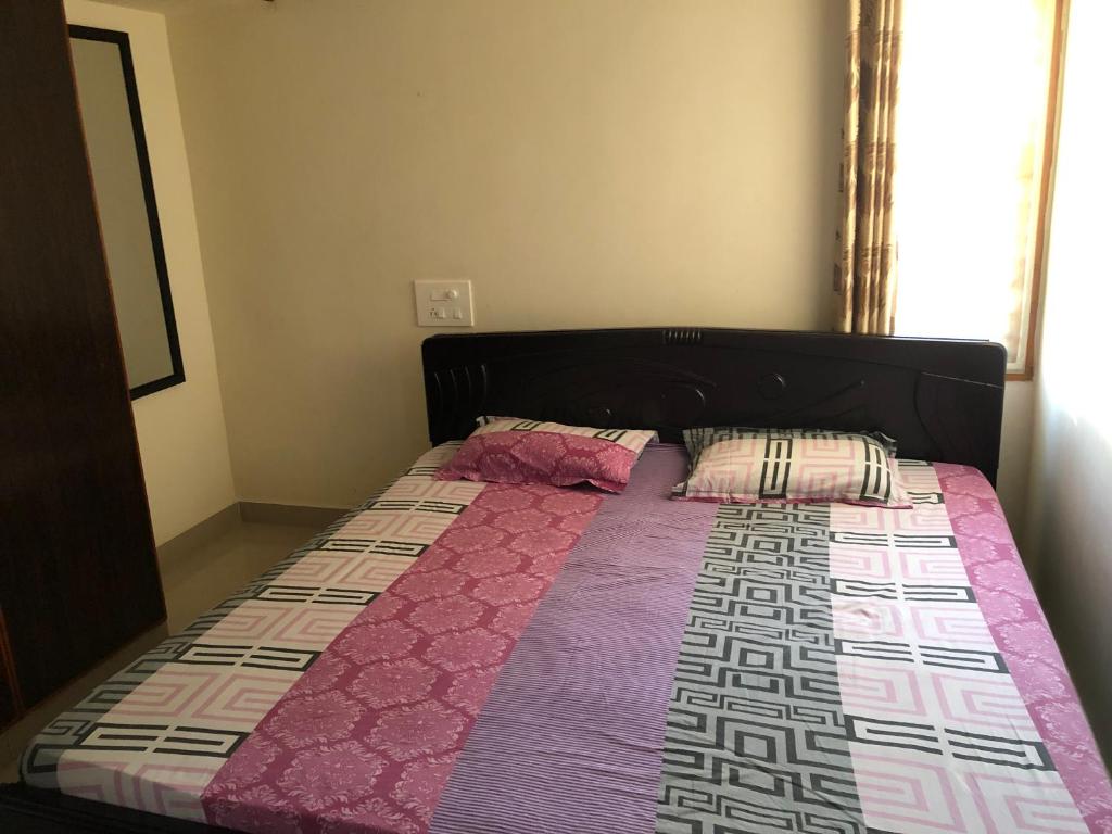 uma cama com um edredão rosa e roxo num quarto em GIRI Service Apartment em Tirupati
