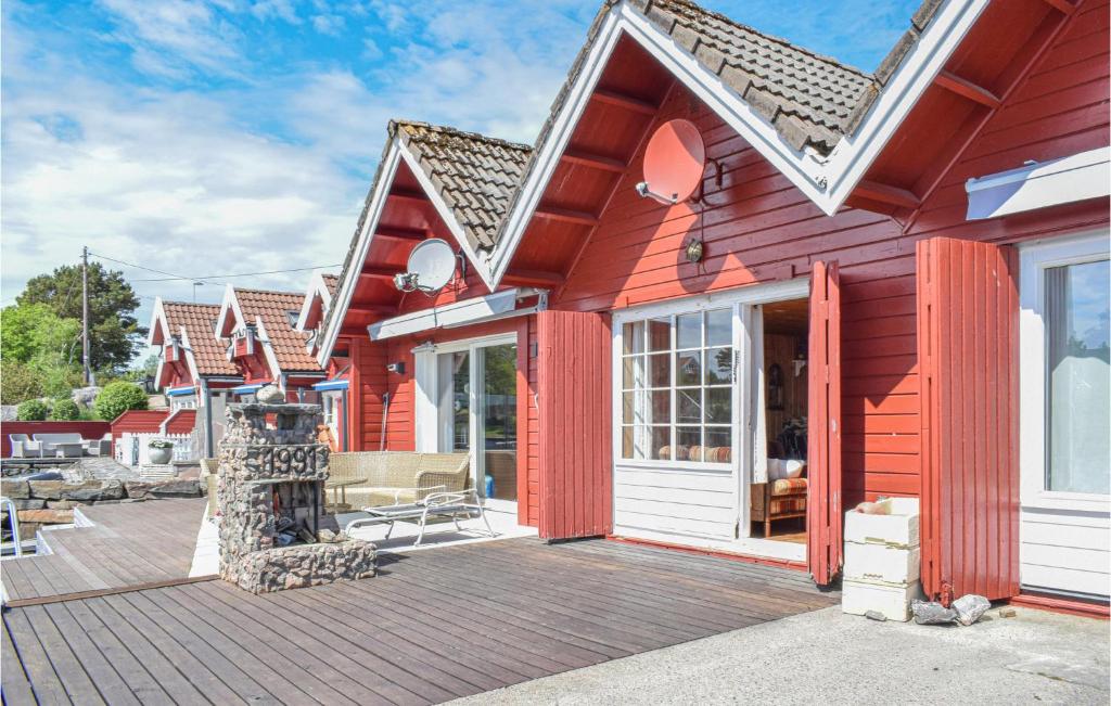 een rood huis met een houten terras bij Lovely Home In Sgne With Wifi in Søgne