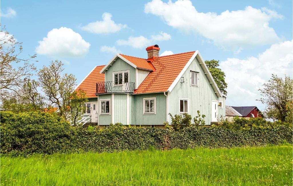 una casa blanca con techo naranja en un campo verde en 4 Bedroom Gorgeous Home In Degerhamn, en Degerhamn