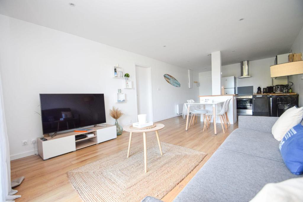 a living room with a couch and a tv and a table at 2 pièces cosy avec terrasse privée 5min à pied de la plage in Dinard