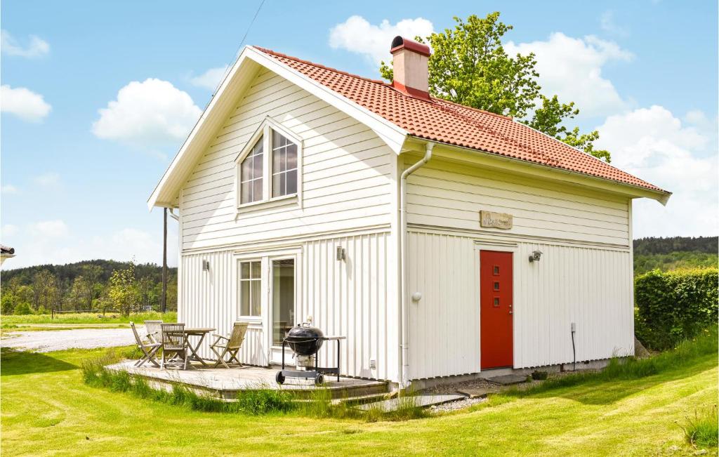 biały domek z czerwonymi drzwiami i grillem w obiekcie Stunning Home In Svanesund With Wifi w mieście Svanesund