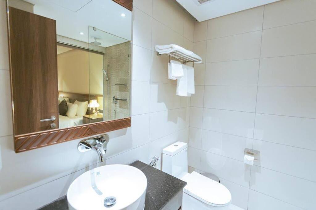 La salle de bains blanche est pourvue d'un lavabo et d'un miroir. dans l'établissement Apec 5 sao TP.Tuy Hòa - View biển và view hồ bơi, à Ðông Tác (1)