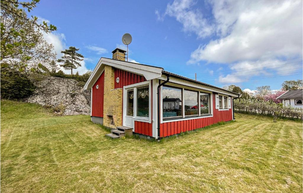 una pequeña casa roja y blanca en un campo de hierba en Amazing Home In Hviksns With Kitchen, en Höviksnäs