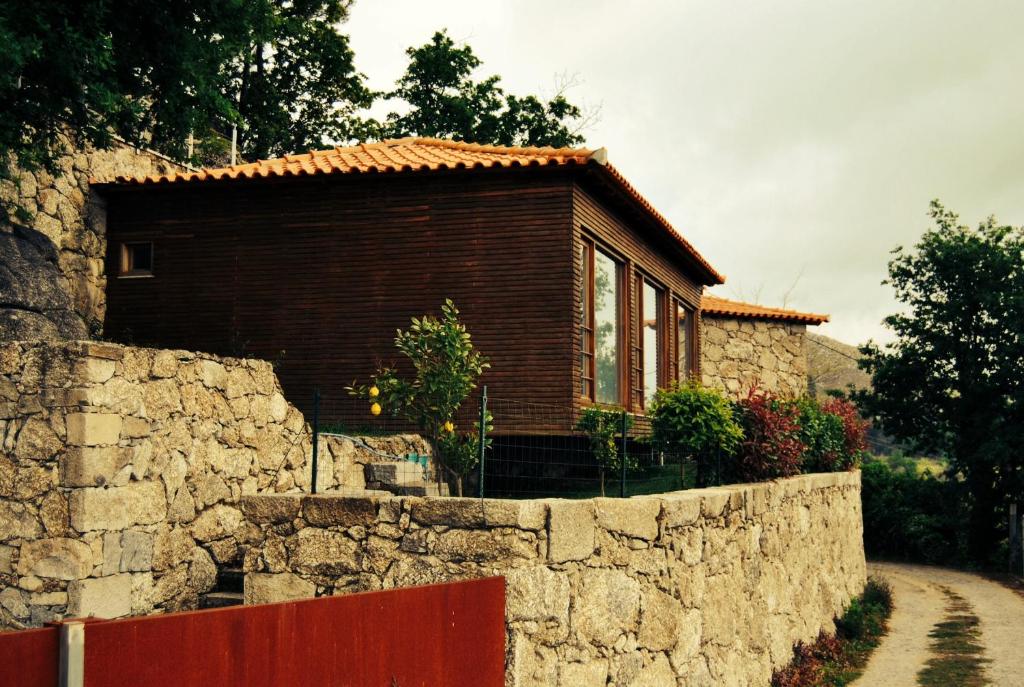 a small house in a stone wall next to a road at Casa Do Fragao in Bouro