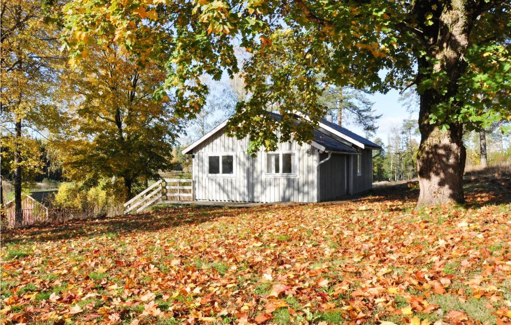 una cabaña blanca con un árbol y hojas en el suelo en Awesome Home In Sffle With House A Panoramic View, en Säffle