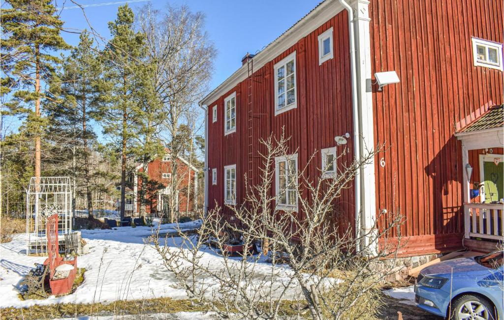 a red house with a car parked in front of it at Stunning Apartment In ngelsberg With Kitchen in Ängelsberg