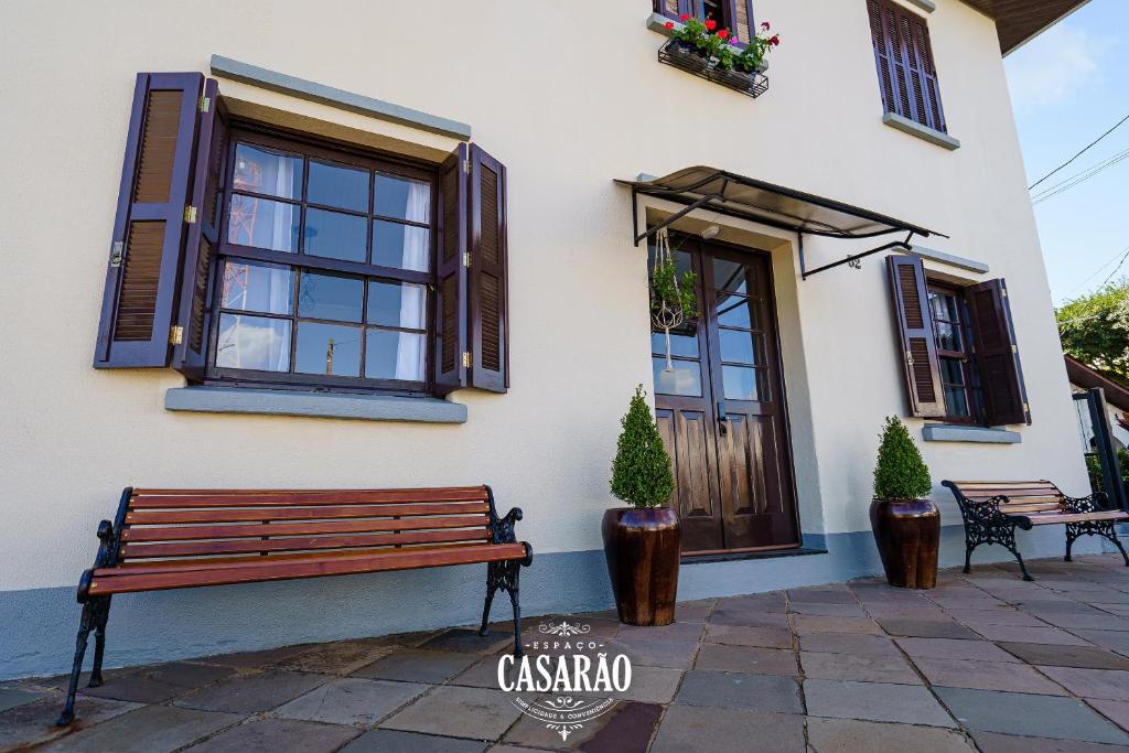 a wooden bench sitting outside of a building with windows at Espaço Casarão - Serra Gaúcha in Cotiporã