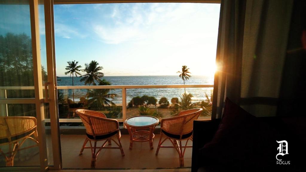een balkon met een tafel en stoelen en uitzicht op de oceaan bij The Beach Front Apartment - Colombo, Uswetakeiyawa, Colombo in Wattala