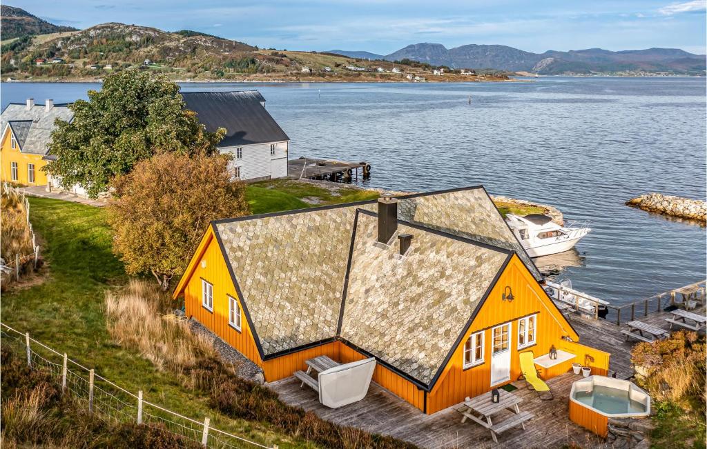 an orange house on the shore of a body of water at Lovely Home In Kvamsy With Jacuzzi in Sandvik