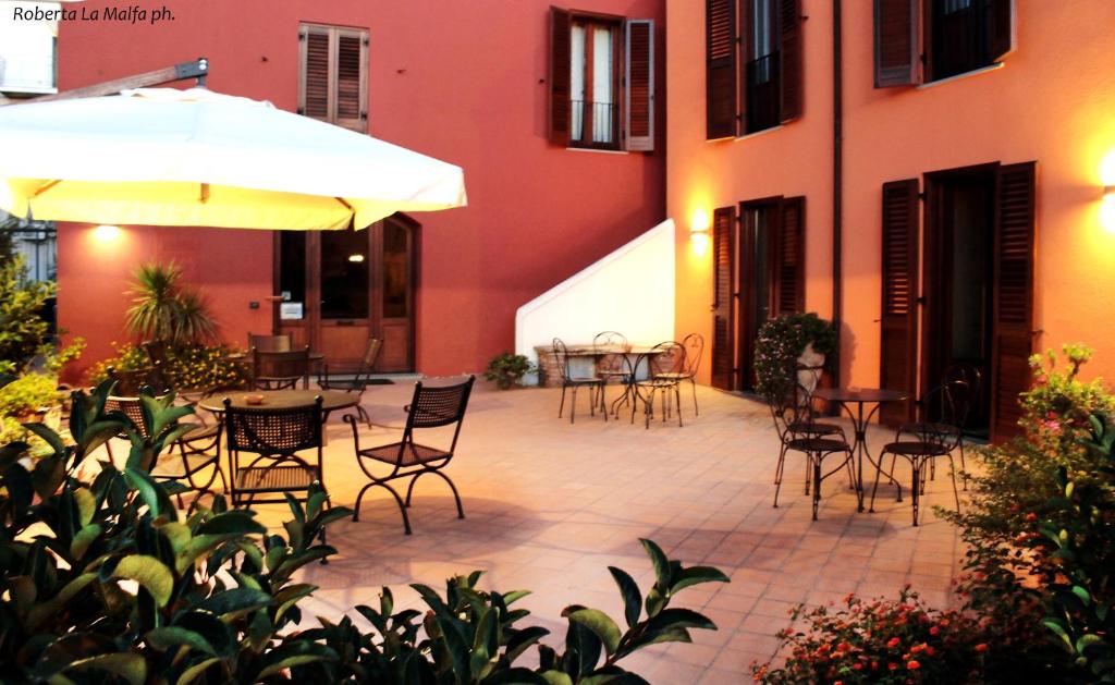 an outdoor patio with chairs and tables and an umbrella at Il Casale dei Conti in Barcellona-Pozzo di Gotto