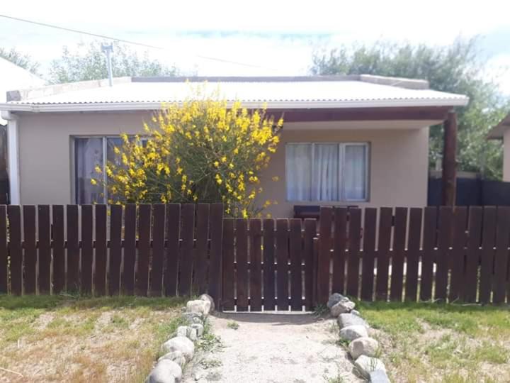 My House in El Calafate في إل كالافاتي: حاجز خشبي أمام المنزل