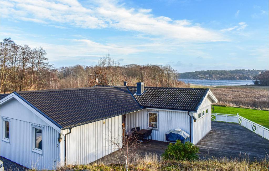 a white cottage with a wooden deck next to the water at Amazing Home In Klövedal With Kitchen in Klövedal