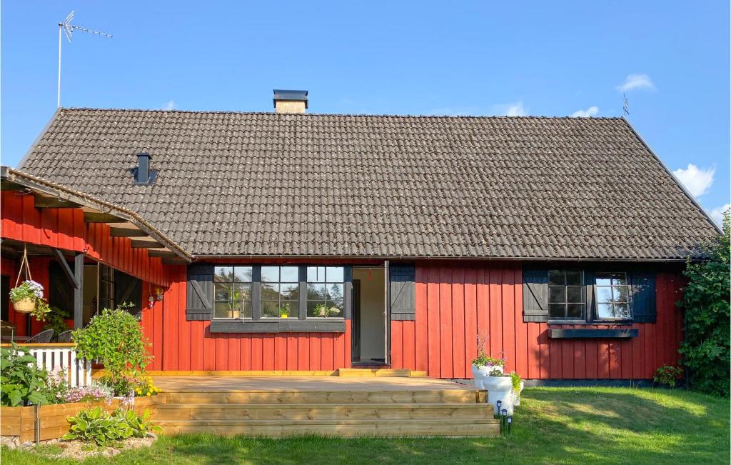une maison rouge avec une terrasse en bois devant elle dans l'établissement Cozy Home In Osby With Wifi, à Osby