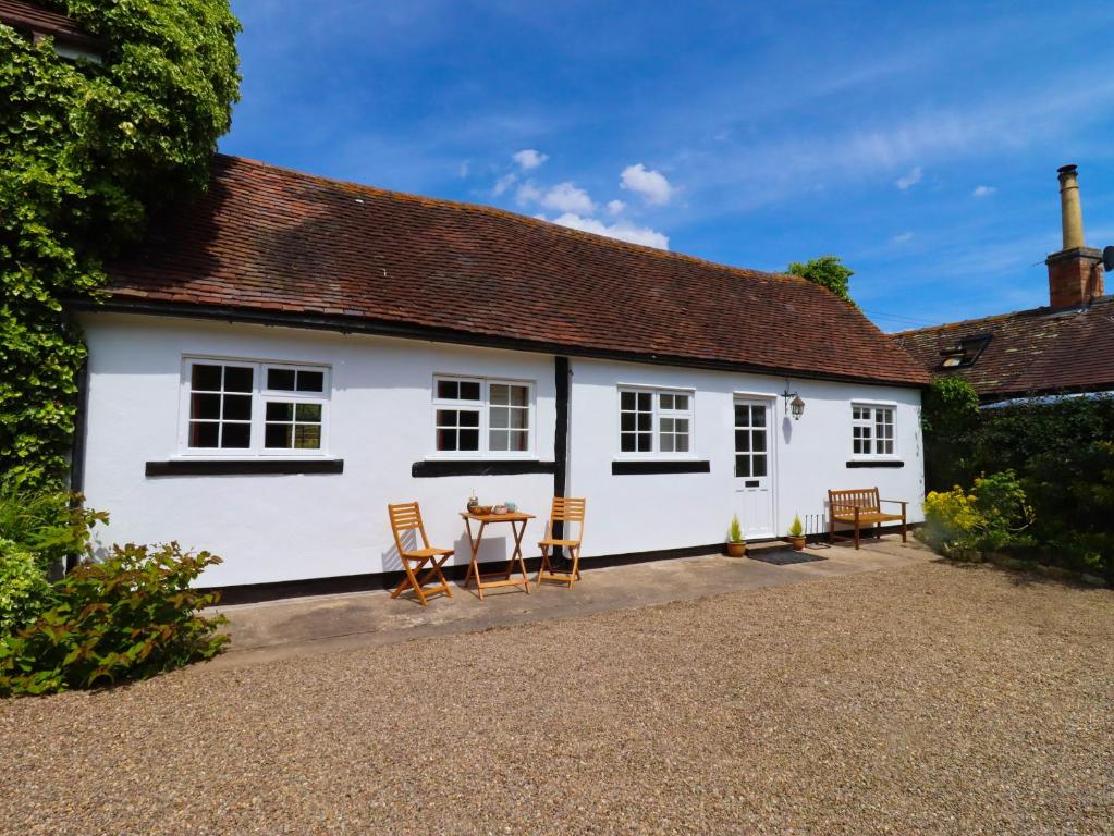 a white house with chairs and a table in front of it at Mortons Cottage in Castlemorton