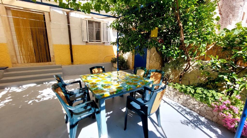 een blauwe tafel met vier stoelen en een tafel met twee honden erop bij Apartment Nadi - 100 m from sea in Unije