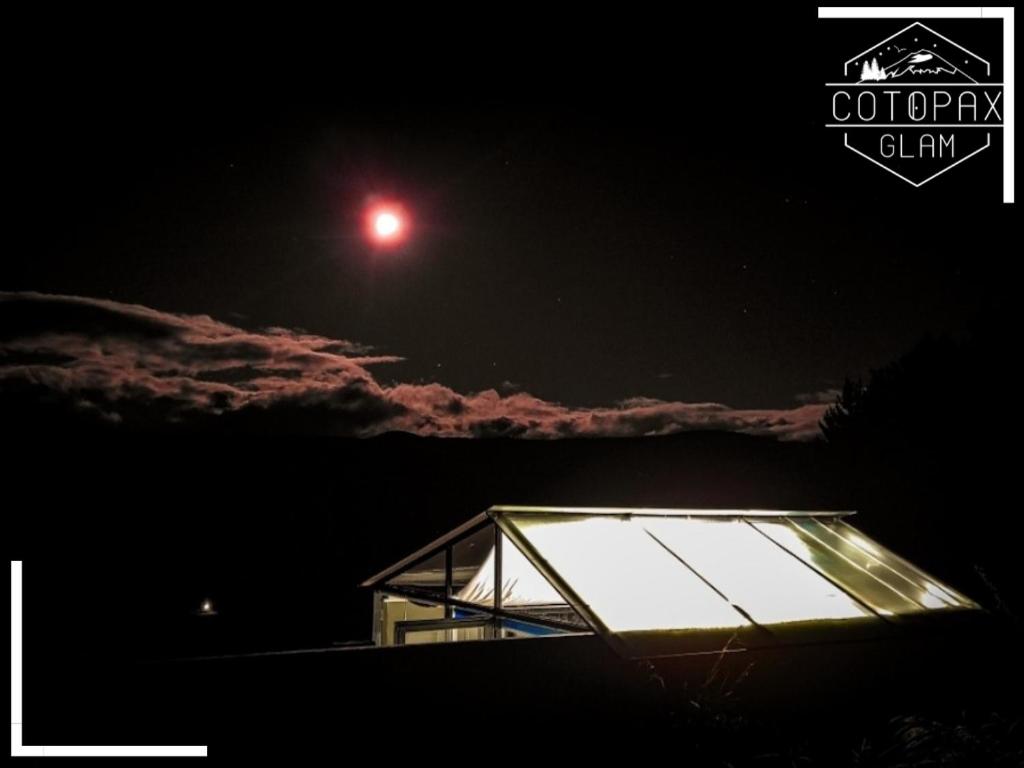 un toit en verre d'un bâtiment la nuit avec la lune dans l'établissement Cotopaxglam, à Latacunga