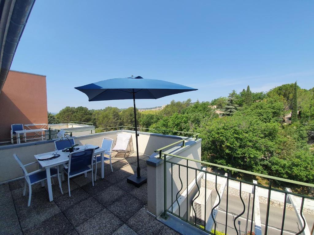 patio ze stołem i parasolem na balkonie w obiekcie Le Blanc-Martel - Piscine, Climatisation & Parking w mieście Gréoux-les-Bains