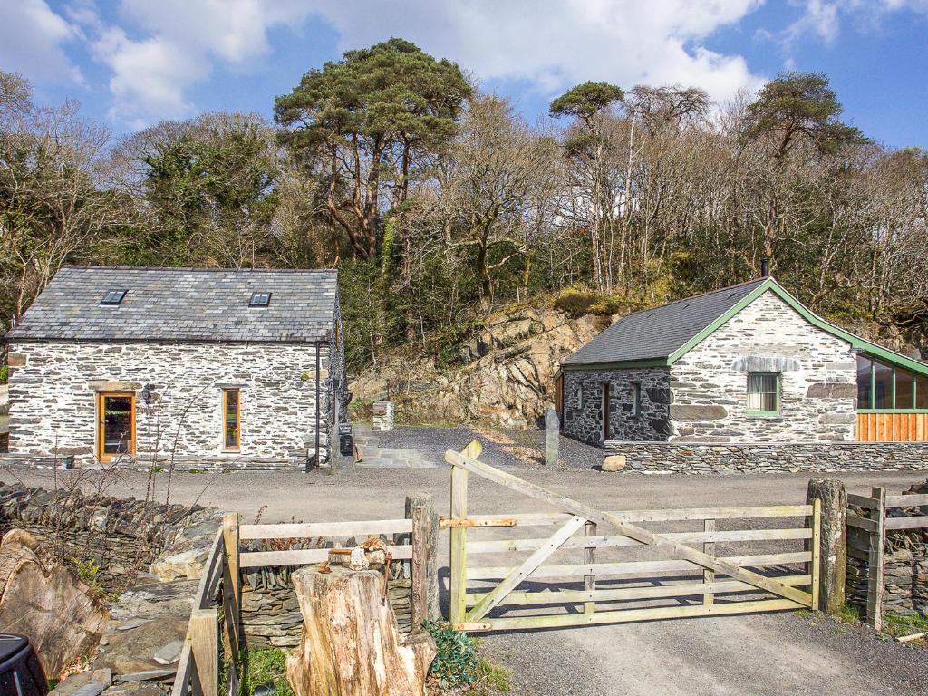 a stone cottage with a gate and a barn at Tyn Llwyn Cornel Eco Barn in Penrhyndeudreath