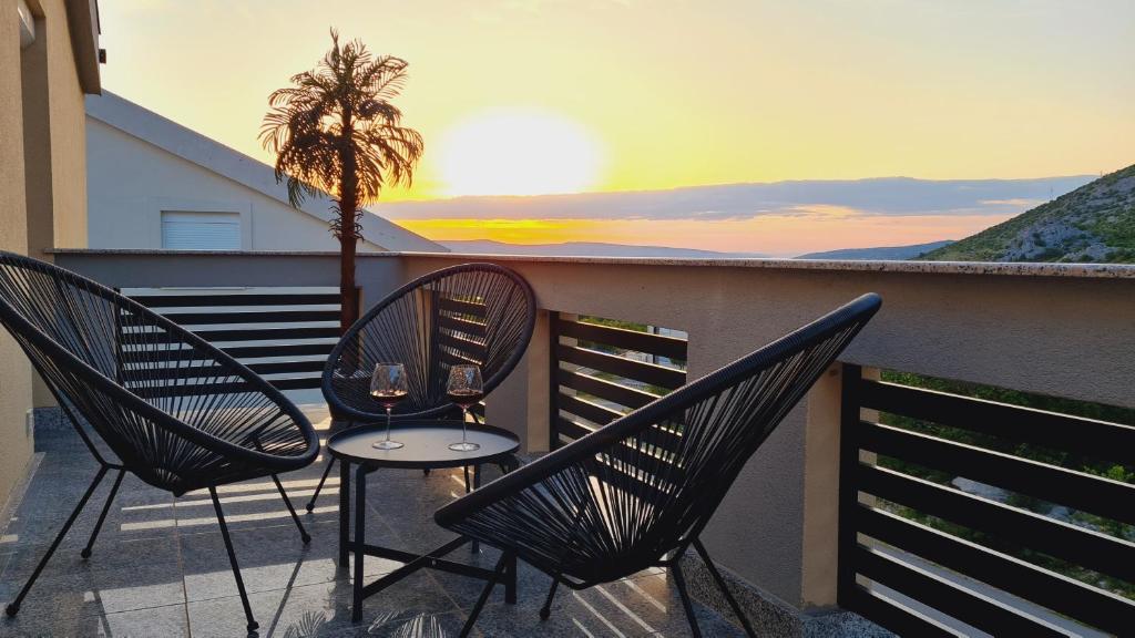 eine Terrasse mit 2 Stühlen und einem Tisch mit Weingläsern in der Unterkunft Villa Silente in Karlobag