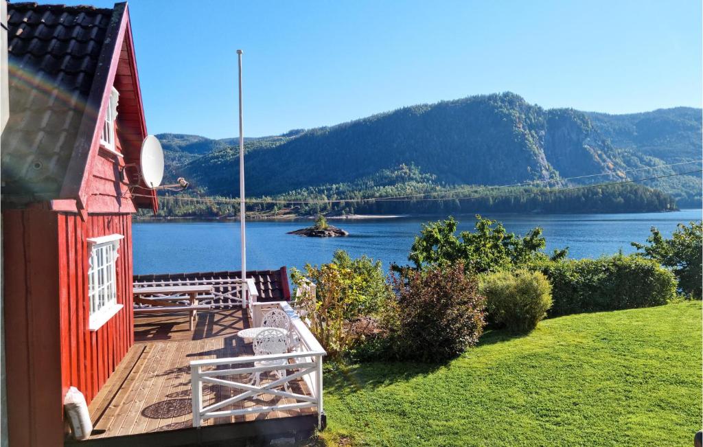 a red house with a deck with a view of a lake at Amazing Home In Bygland With 2 Bedrooms in Bygland