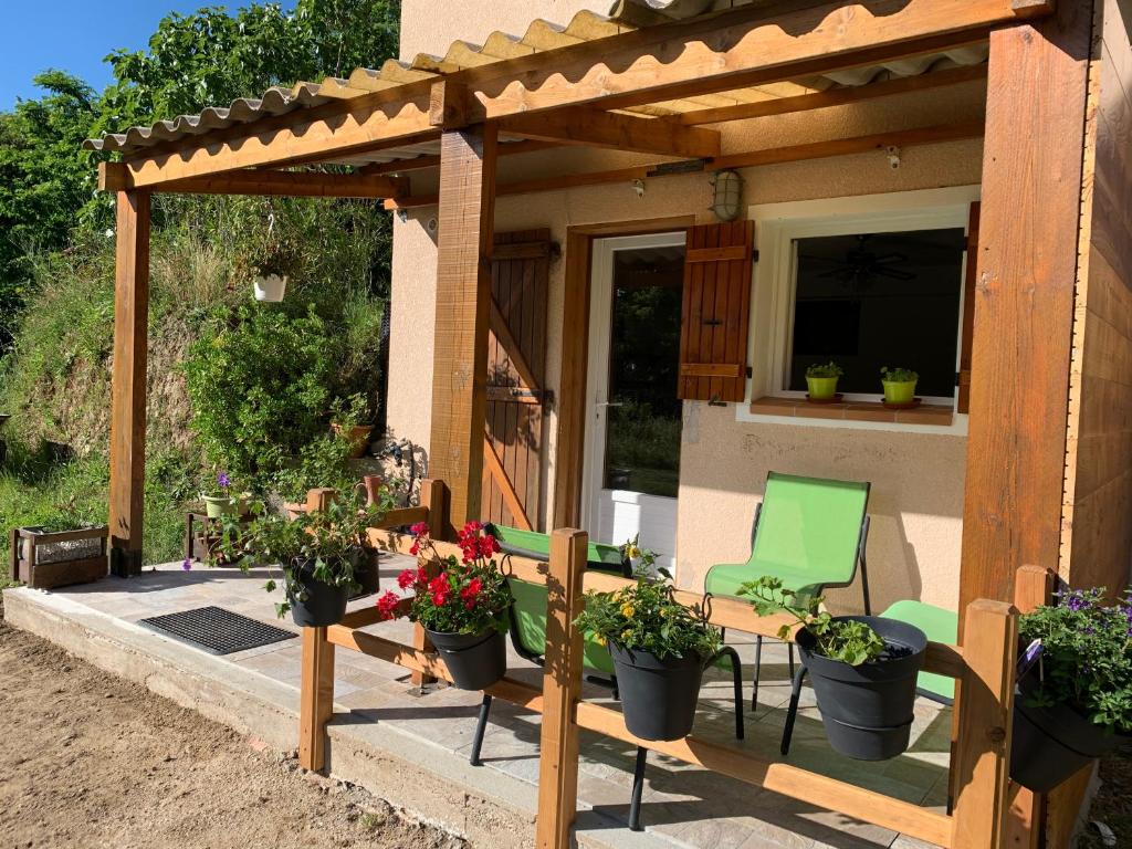 une pergola en bois avec des chaises et des plantes en pot sur une terrasse dans l'établissement A CANTINA, à Ucciani