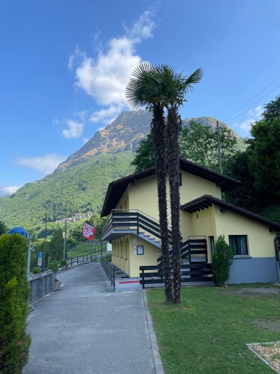 a palm tree in front of a building with a mountain at Osteria Posse in Lavertezzo