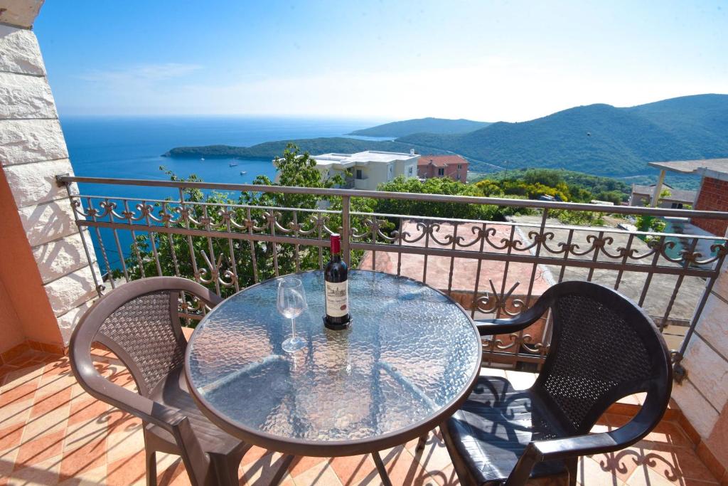 a glass table with a bottle of wine on a balcony at Apartments Villa Sveti Nikola in Budva