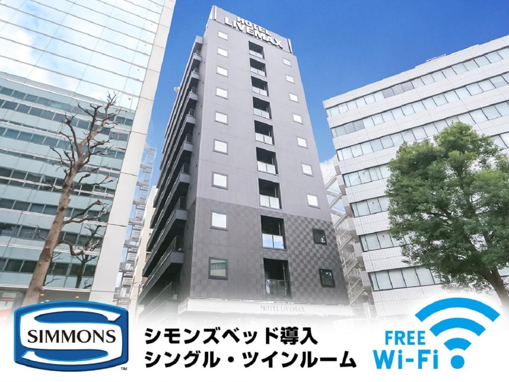 un edificio alto con un cartel delante en HOTEL LiVEMAX Yokohama-Eki Nishiguchi en Yokohama