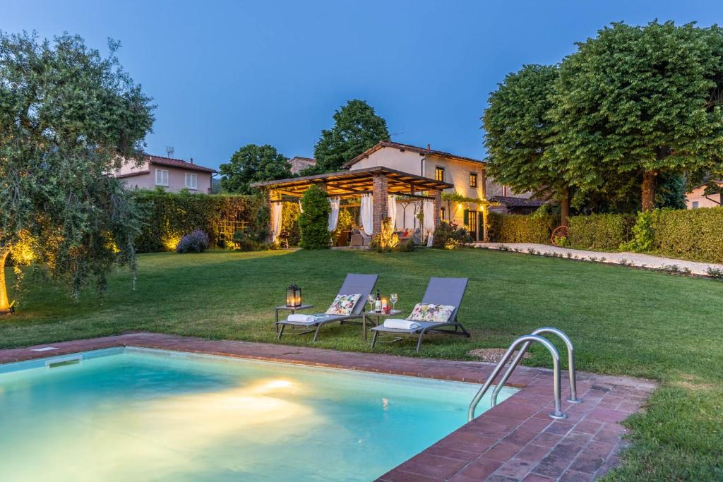 una piscina in un cortile con due sedie e una casa di Pennecchio a Lucca