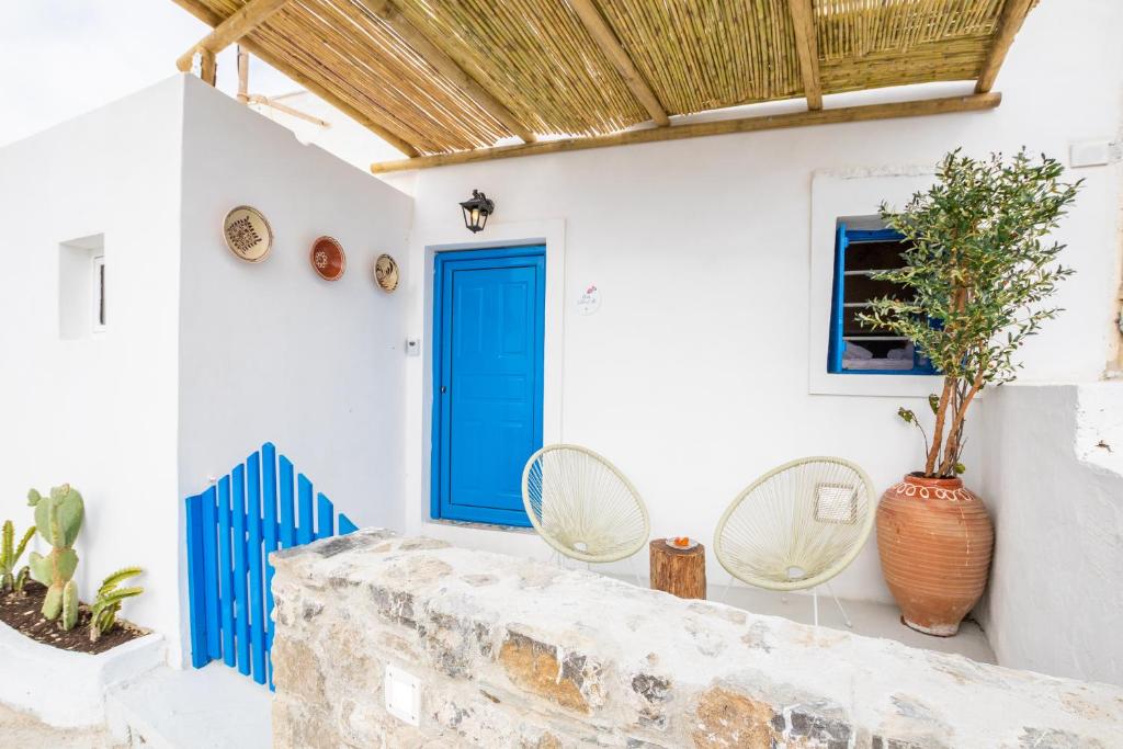 a house with a blue door and two chairs at Nisos Villa Olympos Karpathou in Olympos