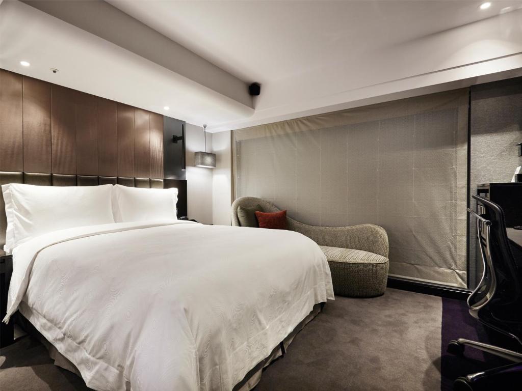 a bedroom with a large white bed and a chair at The Tango Hotel Taipei FuHsing in Taipei