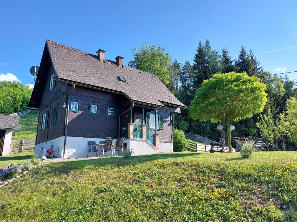 Knusperhaus Ogris في Trieblach: منزل أسود مع شرفة وحديقة