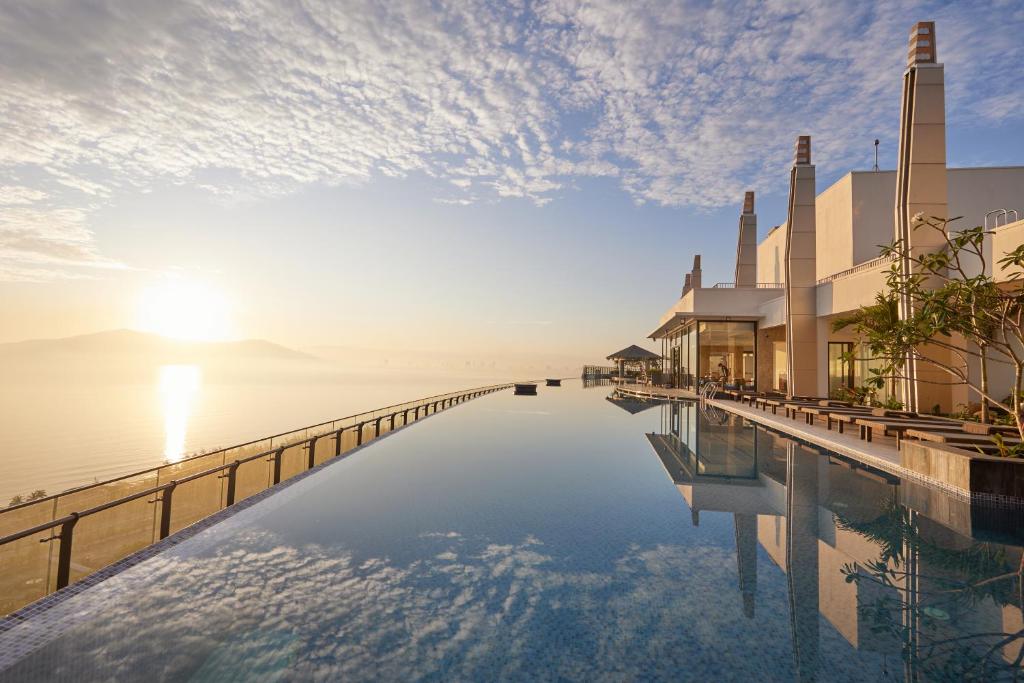 uma piscina com o pôr do sol sobre a água em Da Nang - Mikazuki Japanese Resorts & Spa em Da Nang