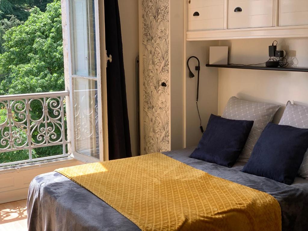 1 dormitorio con cama y ventana grande en PYRENE HOLIDAYS 3 étoiles lumineux dans immeuble atypique proche des thermes et des Pyrénées en Capvern
