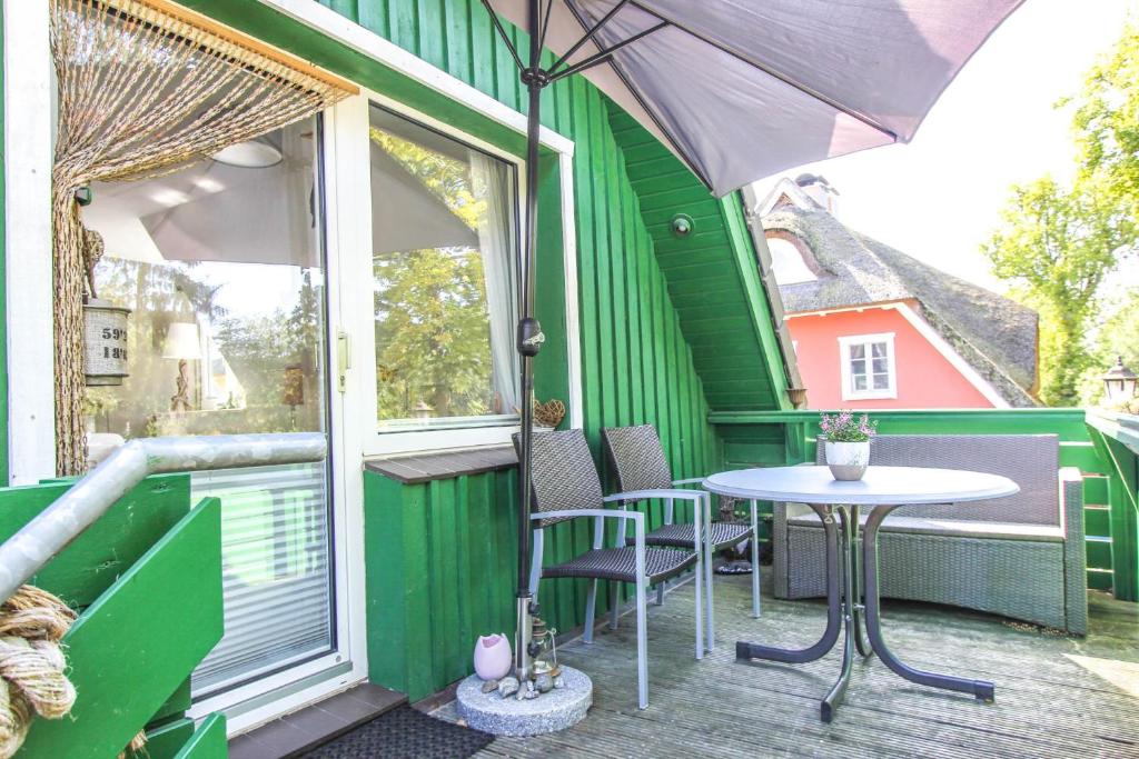 ein grünes Haus mit einem Tisch und Stühlen auf dem Balkon in der Unterkunft Am Waldesrand in Prerow
