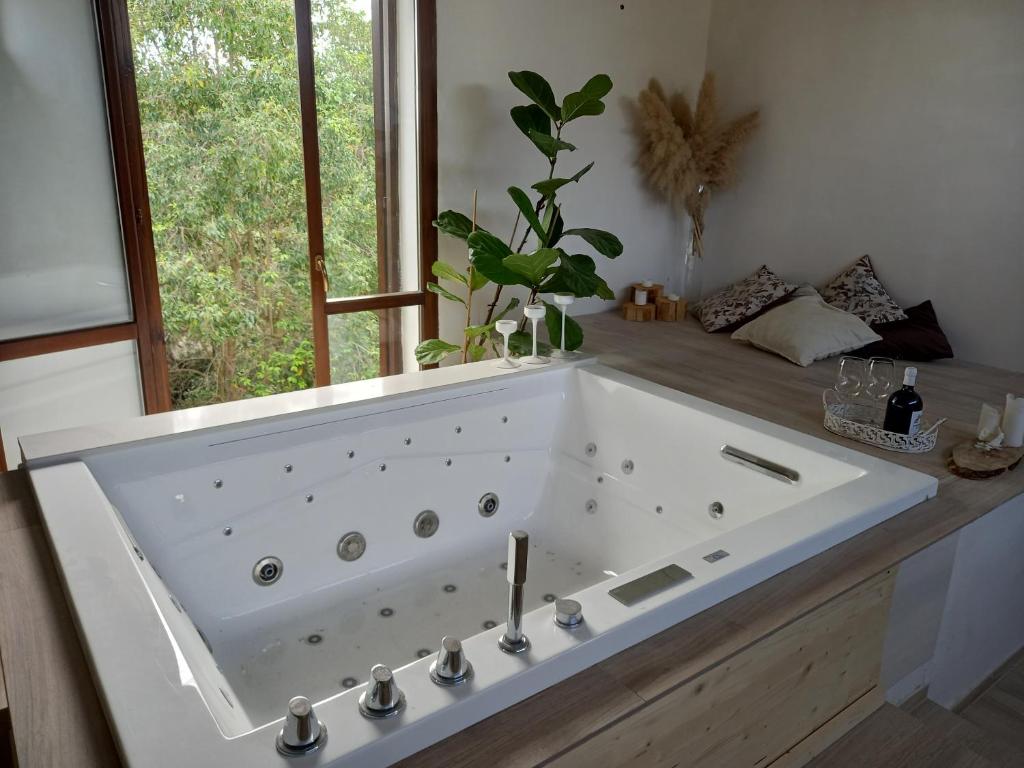 une grande baignoire blanche dans une salle de bain avec une fenêtre dans l'établissement MASSERIA INCANTAMENTO Suite Bouganville, à Latiano