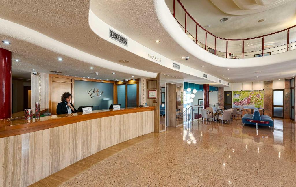 a woman standing at a reception desk in a lobby at Perla Marina in Nerja