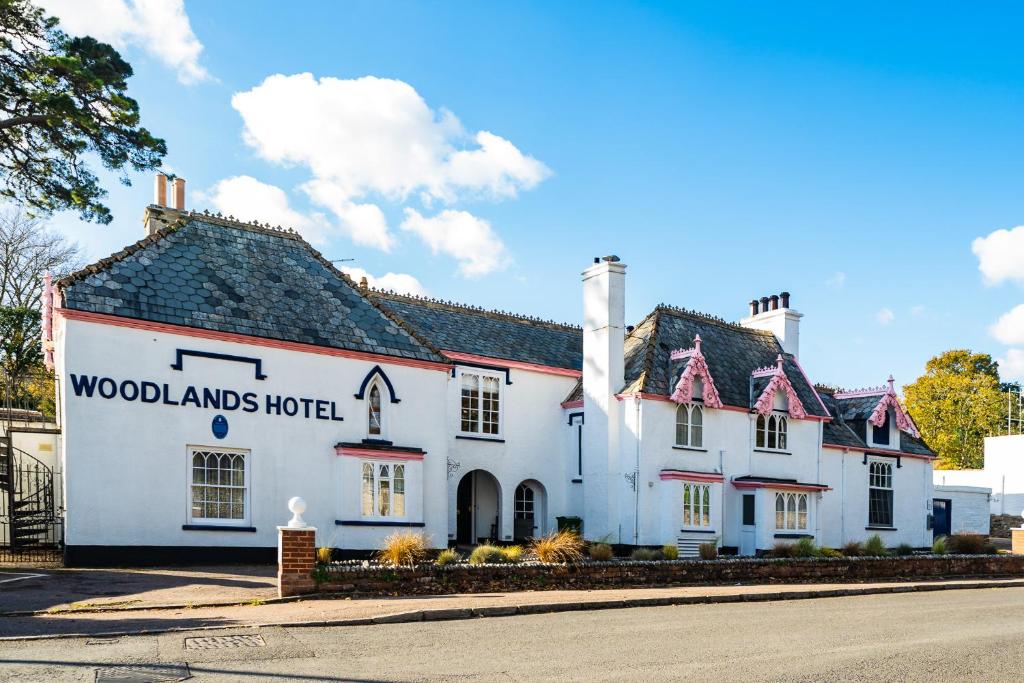 een witte herberg met een bord dat een hotel in de bossen leest bij The Woodlands Hotel in Sidmouth