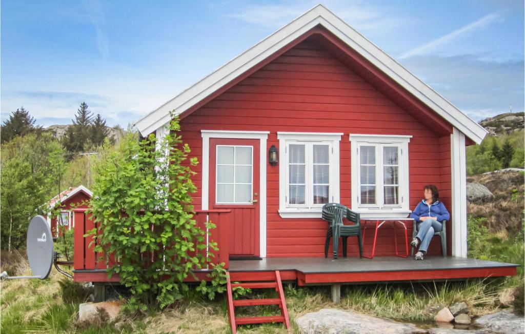 een vrouw die op de veranda van een rood huis zit bij Awesome Home In Spangereid With Kitchen in Korshamn