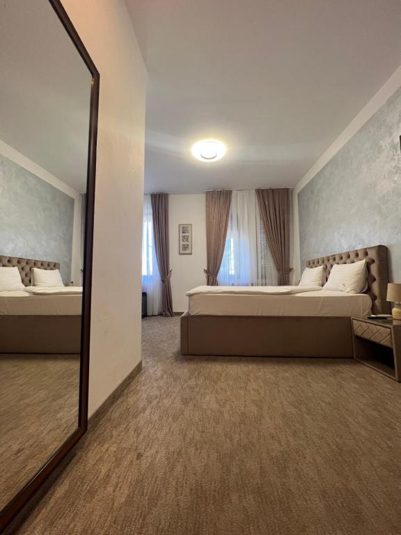- une grande chambre avec 2 lits et un miroir dans l'établissement Casa Mignon, à Oradea