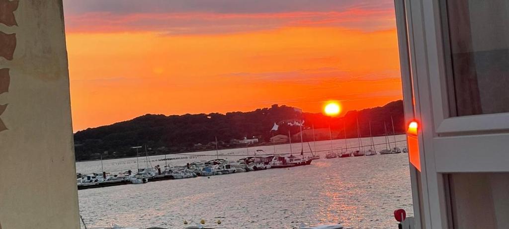 una ventana con vistas a la playa al atardecer en Bel appartement sur le port du Brusc avec sa place de parking privative. en Six-Fours-les-Plages