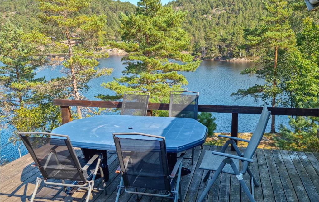 a blue table and chairs on a deck with a view of a lake at 3 Bedroom Amazing Home In Sgne in Søgne