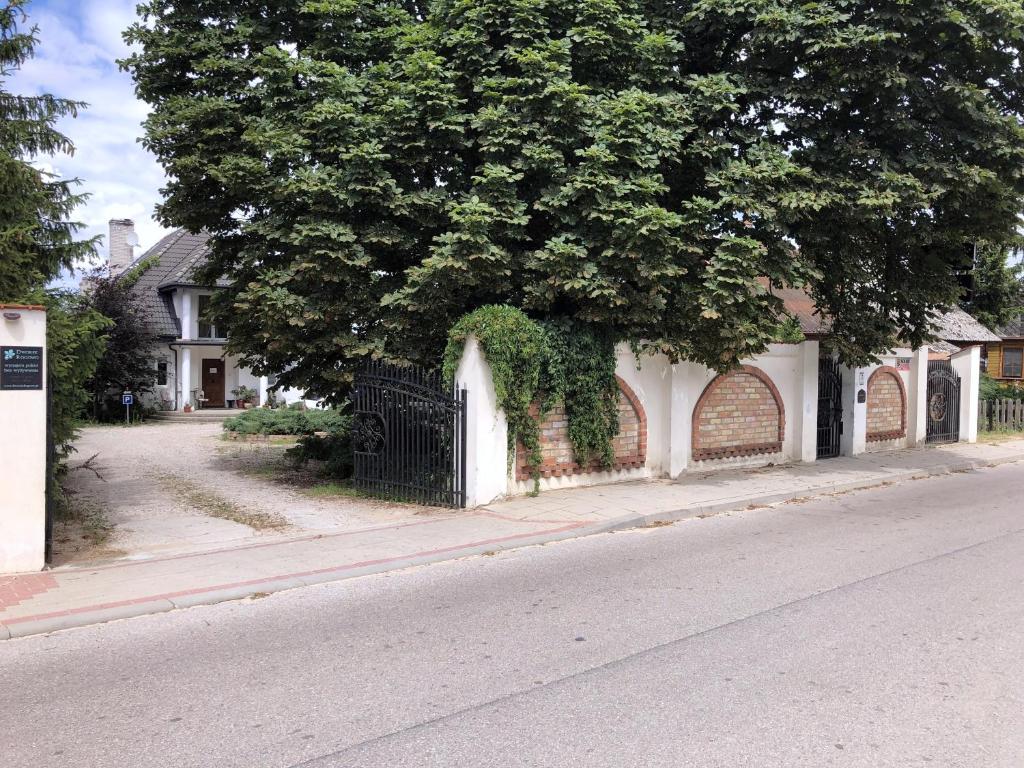 a fence on the side of a street with a tree at Dworek Rogowo in Choroszcz