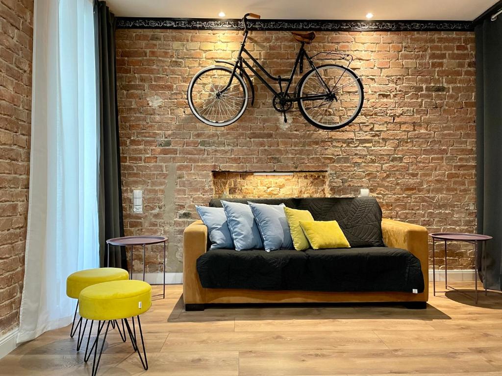 a bike hanging on a brick wall above a couch at Petite Viste No. 3 Apartment in Toruń