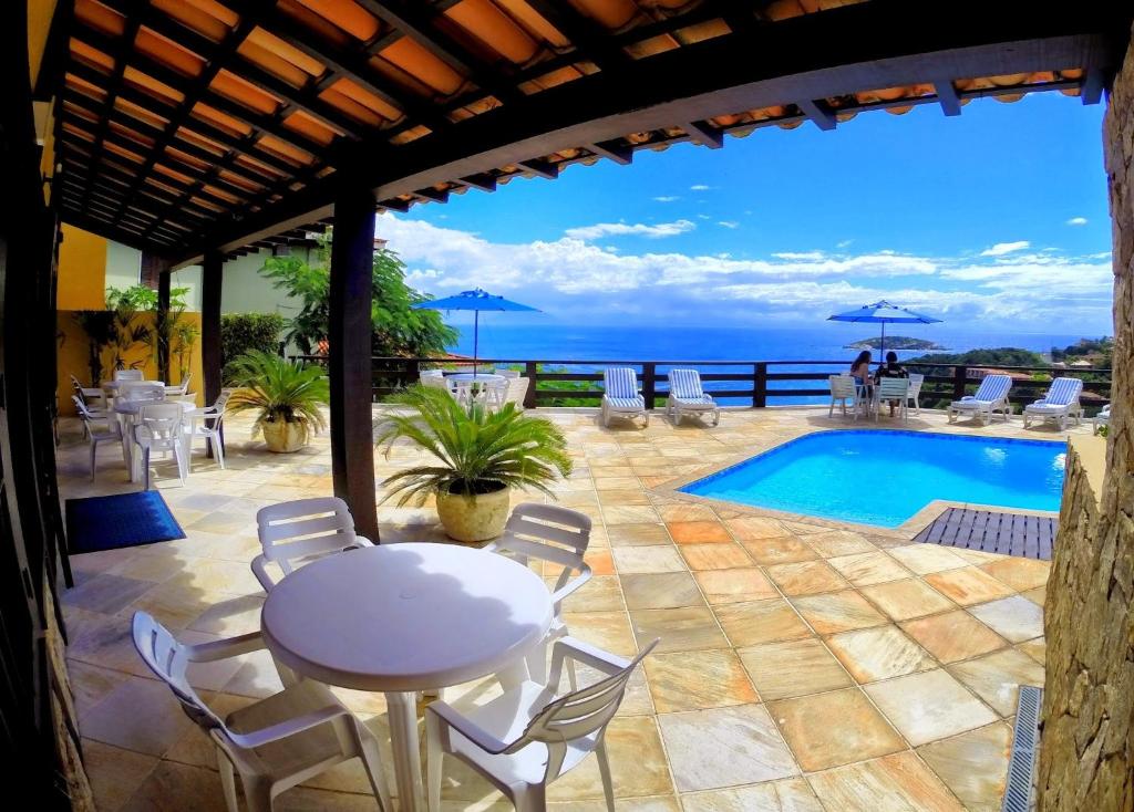 ブジオスにあるPousada Gente Bonita Miranteのテーブルと椅子とプールのあるパティオ