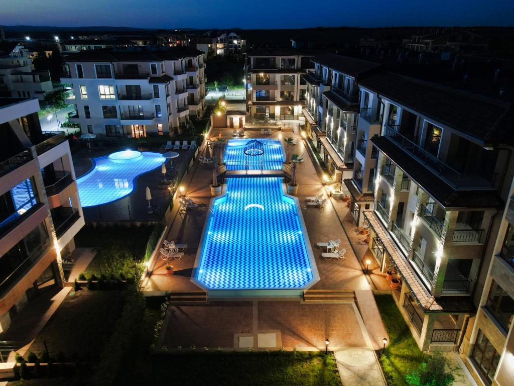 una vista panoramica su una piscina in una città di notte di Burgas Beach Resort 2 Apartments a Burgas