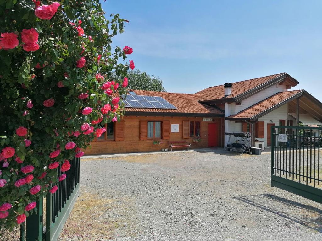 Una casa con una cerca con rosas. en Agriturismo bio Apipoli en Lucino