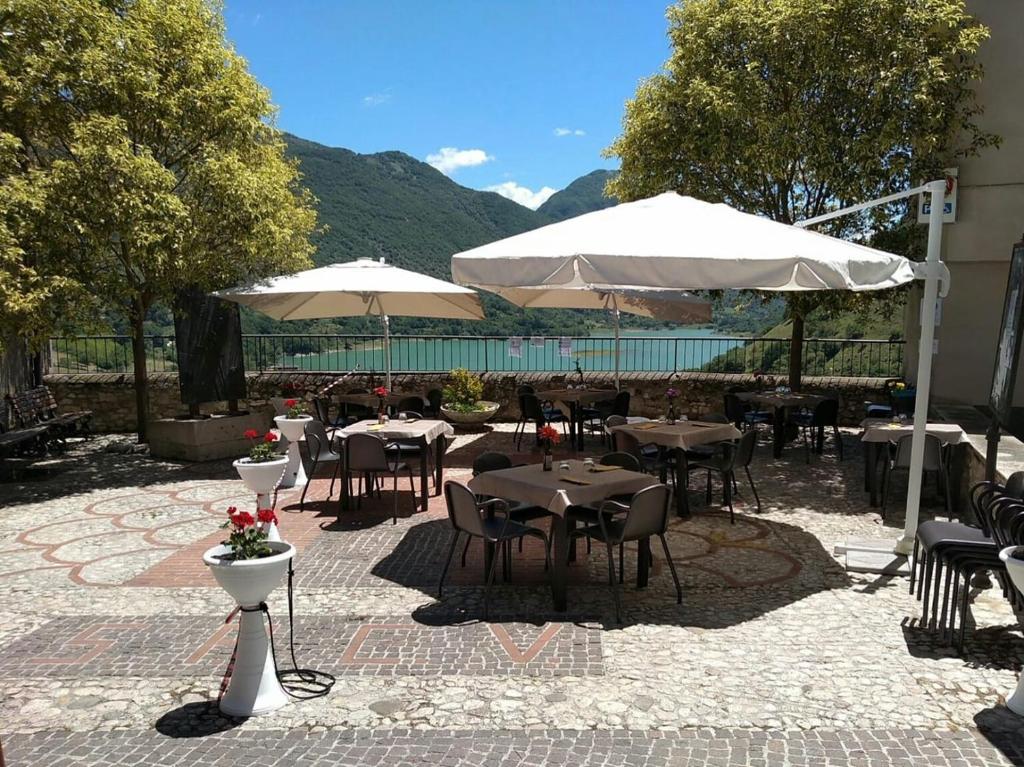 a patio with tables and white umbrellas at La Minicasa al Lago del Turano in Castel di Tora